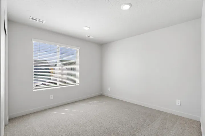 Carpeted room featuring a large window with blinds, recessed lighting, and light gray painted walls