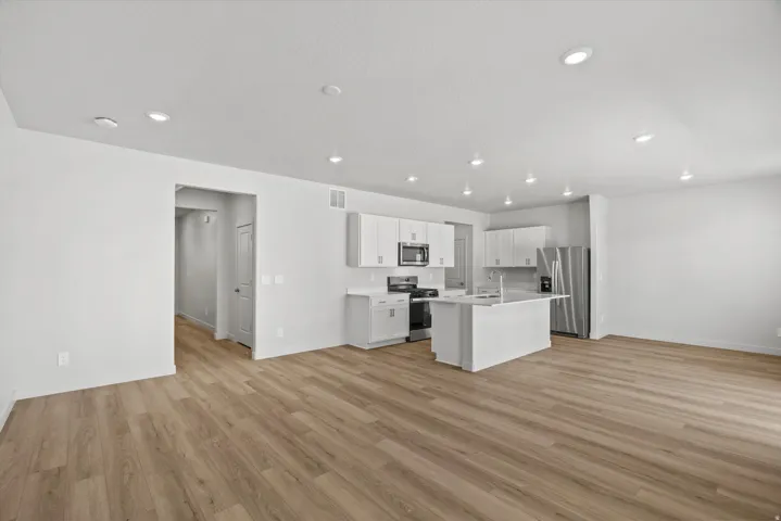 Open-concept interior featuring light wood-finish flooring, recessed lighting, and a modern kitchen