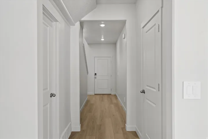 Hallway featuring wood-finish flooring, recessed lighting, white paneled doors, and contemporary baseboards