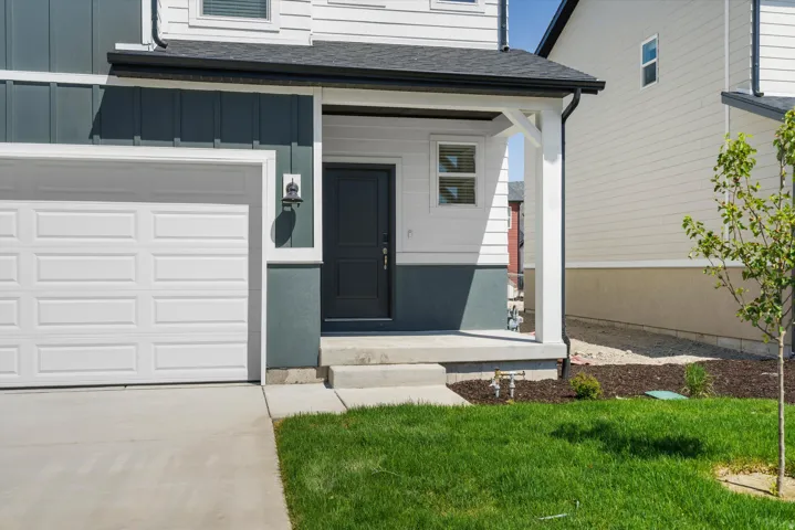 Modern facade featuring a dark gray front door, white paneled garage, and a covered porch entry