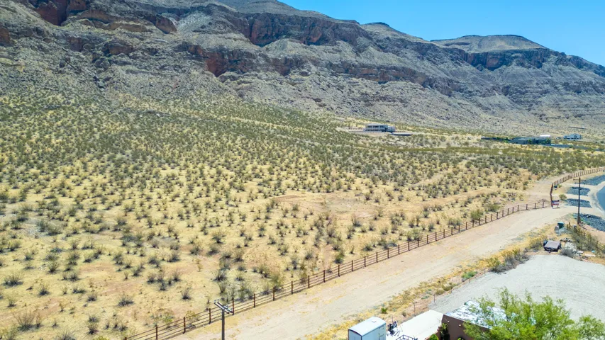 Expansive desert landscape featuring rugged mountain formations, natural vegetation, and a clear sky