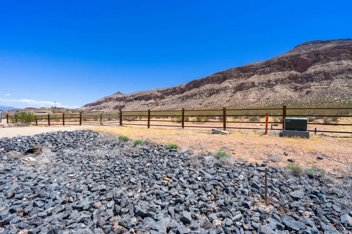 Expansive desert landscape with a rock-filled drainage area and a wood-post fence