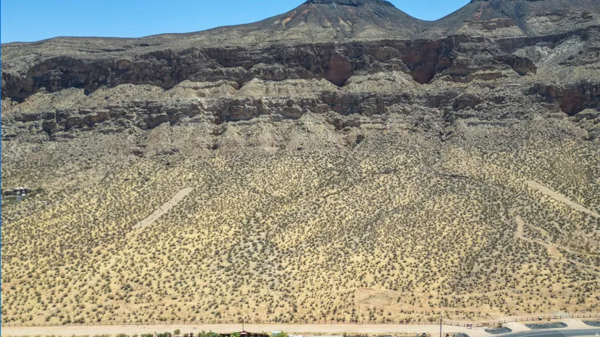 Expansive desert landscape featuring rugged mountain formations, natural rock outcroppings, and sparse native vegetation