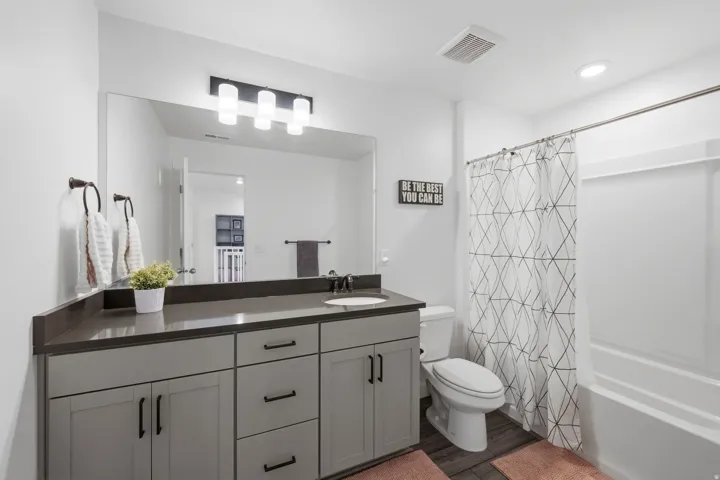 Bathroom featuring a gray vanity with black hardware, dark countertop, and integrated sink