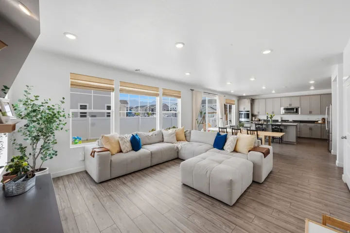 Open-concept living area featuring wood-finish flooring, recessed lighting, and expansive windows with natural light