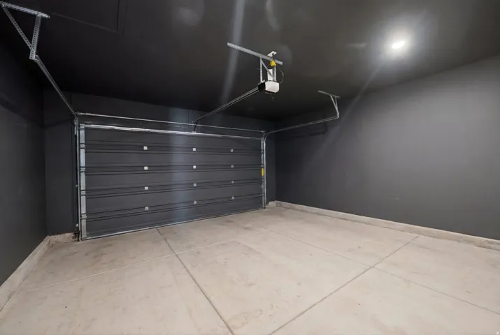 Spacious single-car garage featuring a sectional door, concrete flooring, and an automatic garage door opener