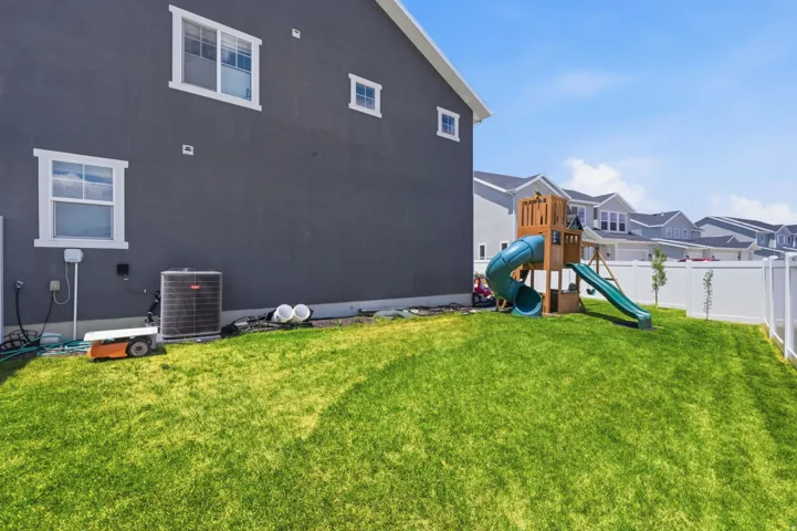 Expansive lawn area featuring a white privacy fence and a dark gray exterior facade