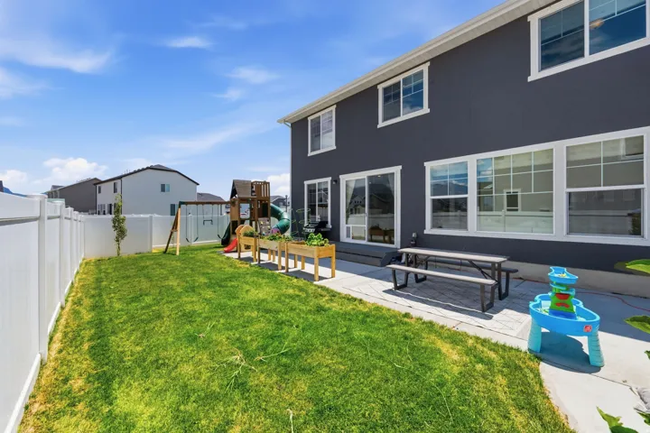 Expansive backyard featuring a manicured lawn, a concrete patio, and a white privacy fence