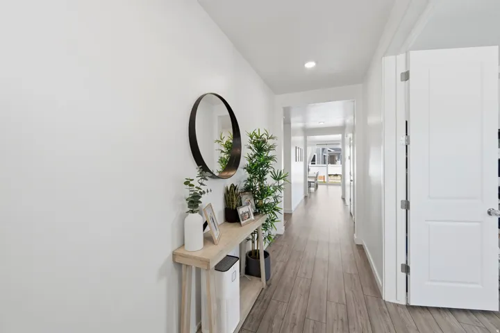 Bright hallway featuring wood-finish flooring, recessed lighting, and a white interior door