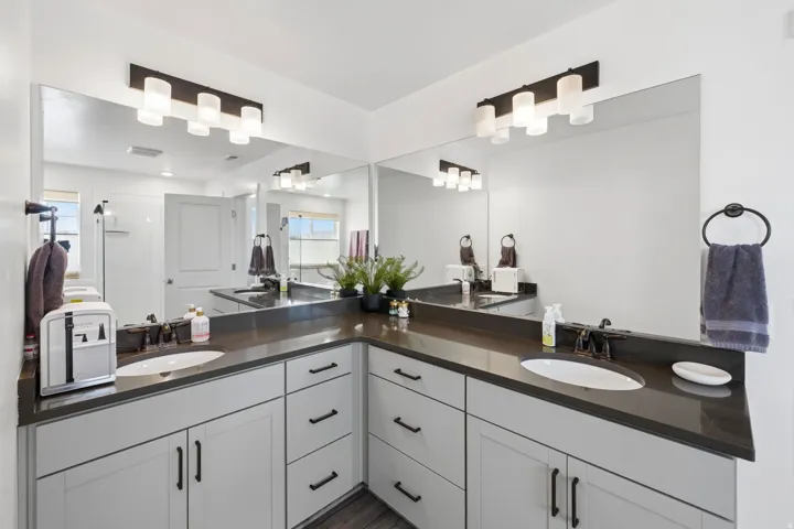 Dual vanity with undermount sinks, dark countertops, and shaker-style cabinetry