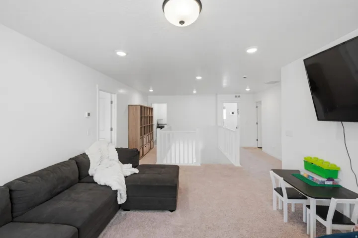 Spacious upper-level area featuring light-colored carpeting, white walls, and recessed lighting