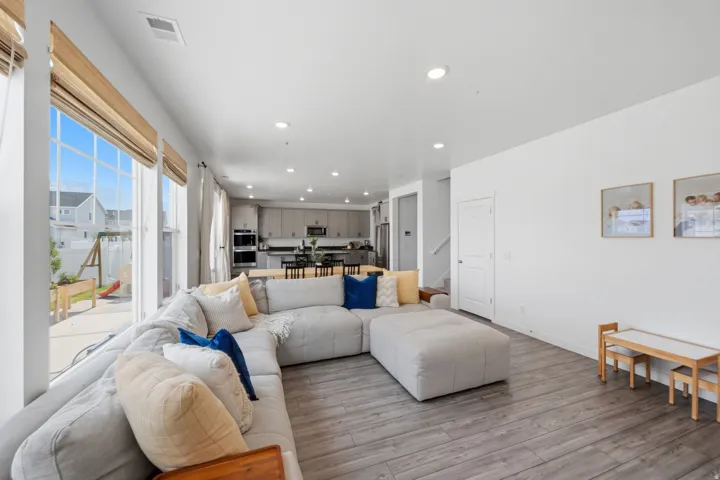 Open-concept living area with wood-finish flooring, ample natural light from large windows, and recessed lighting