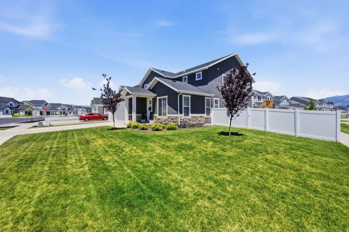 Contemporary two-story residence featuring dark siding, stone veneer accents, and a white picket fence