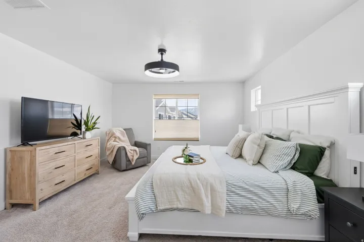 Spacious bedroom featuring light-toned carpeting and a paneled accent wall
