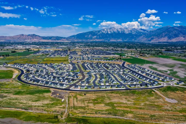 Expansive aerial capturing a contemporary residential development with numerous homes, structured street layouts, and a prominent roundabout