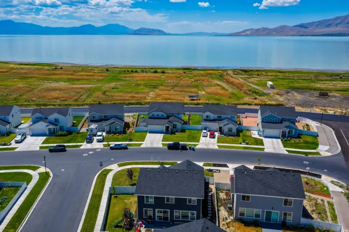 Residential development featuring varied exterior home designs, asphalt roadways, concrete sidewalks, and manicured lawns