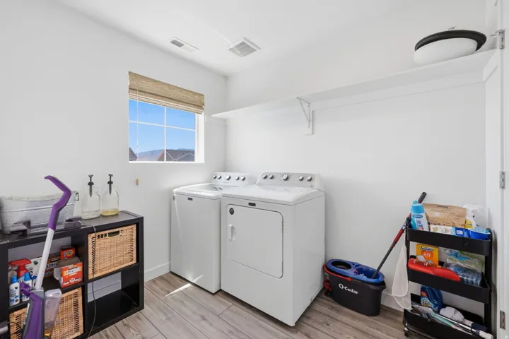 Laundry area featuring wood-finish flooring and a window with a woven shade