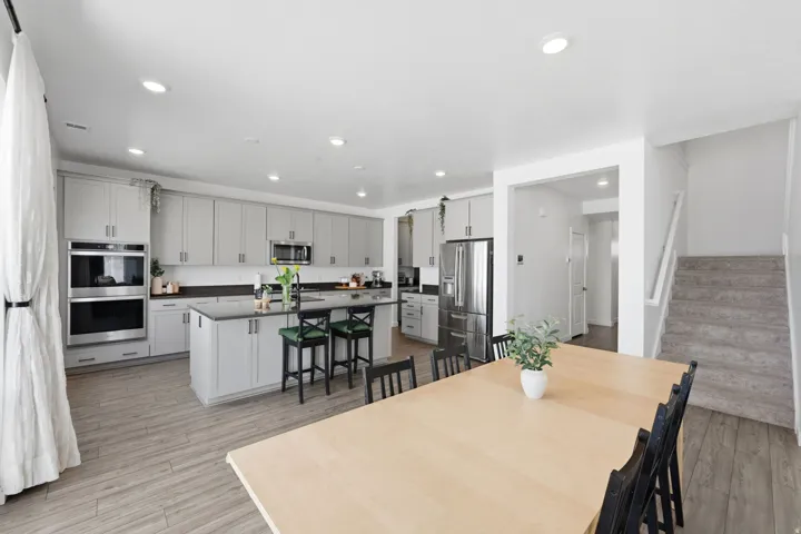 Modern kitchen featuring light gray cabinetry, dark countertops, a stainless steel double oven, and recessed lighting