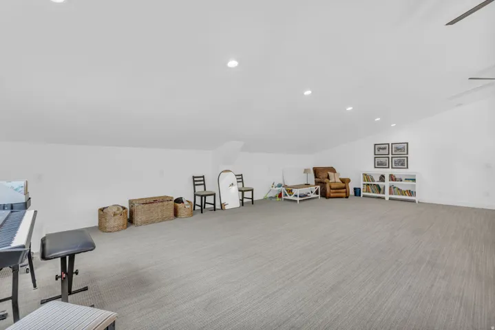 Spacious carpeted room featuring recessed lighting, a sloped ceiling, and a ceiling fan