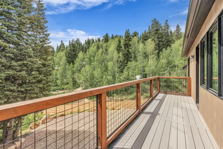 Spacious outdoor deck featuring composite decking, wood-toned railings with metal infill, and exterior wall sconces
