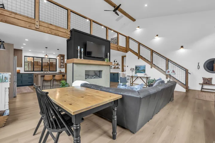 Open-concept living area with vaulted ceilings, light wood-finish flooring, and a modern fireplace