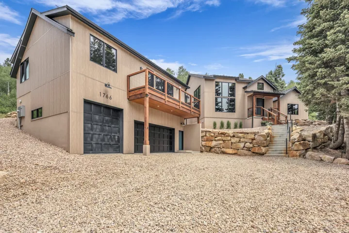 Contemporary exterior with multiple garage bays, a raised wood deck, and a gravel driveway