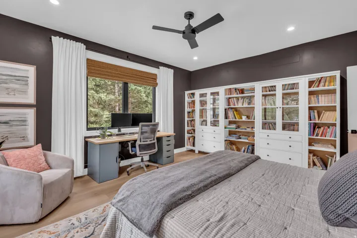 Spacious room featuring extensive built-in white cabinetry with glass-front doors, a dedicated workstation with a wood-finish desktop, and recessed lighting