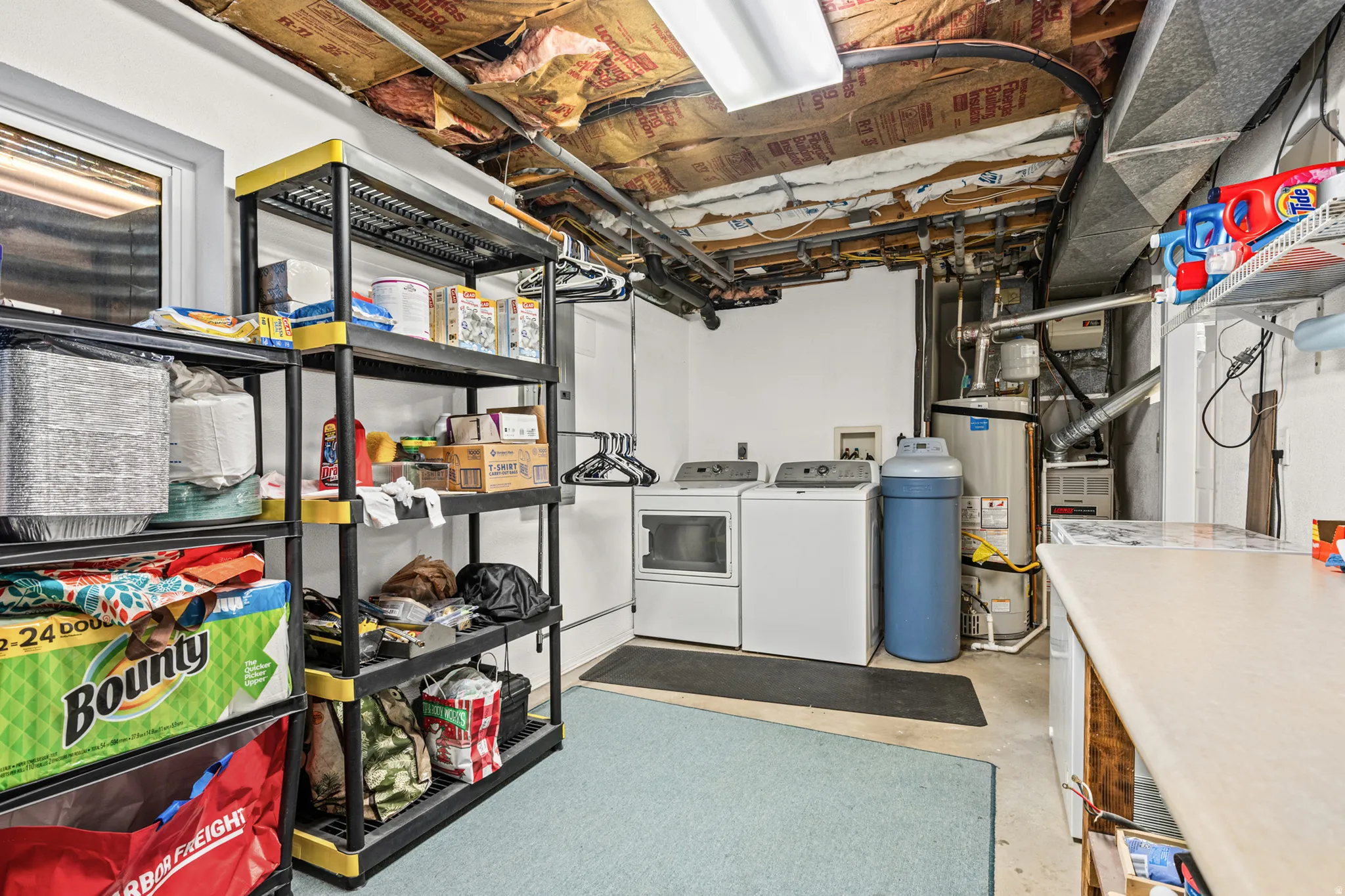 Dedicated laundry area featuring a washer and dryer, utility sink, and additional storage shelving