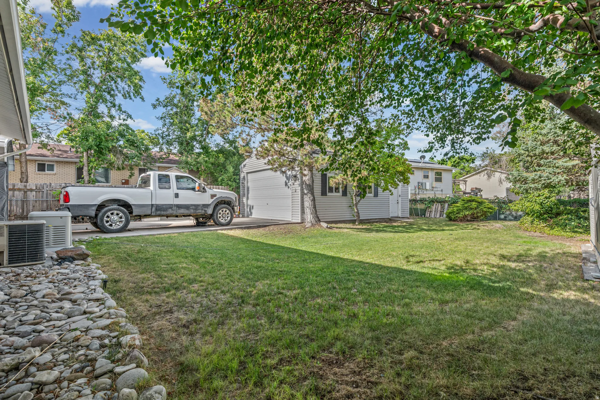 Expansive grassy yard with mature trees and a detached garage