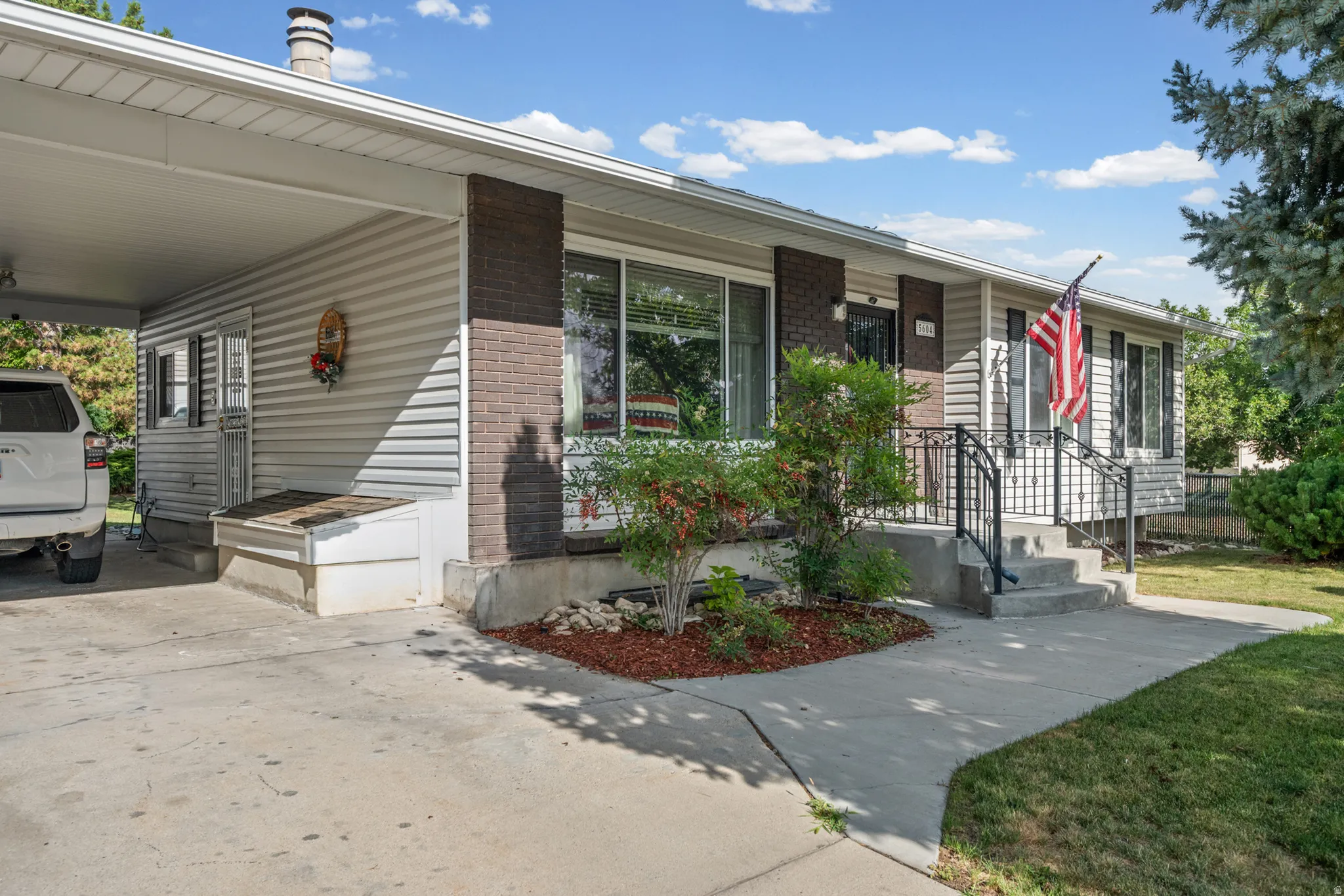 Single-level residence featuring a covered carport, concrete driveway, and established landscaping
