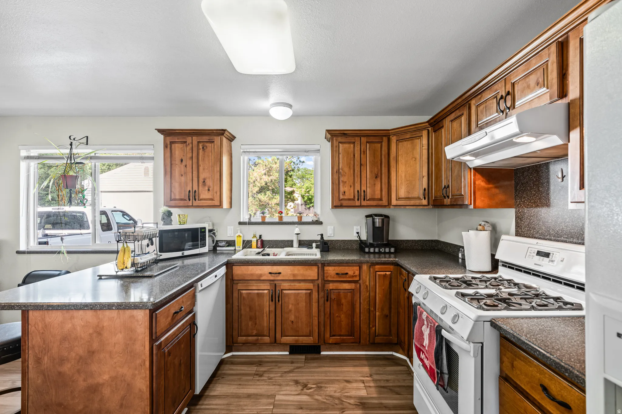 Kitchen featuring wood-finish cabinetry, dark countertops, and wood-finish flooring