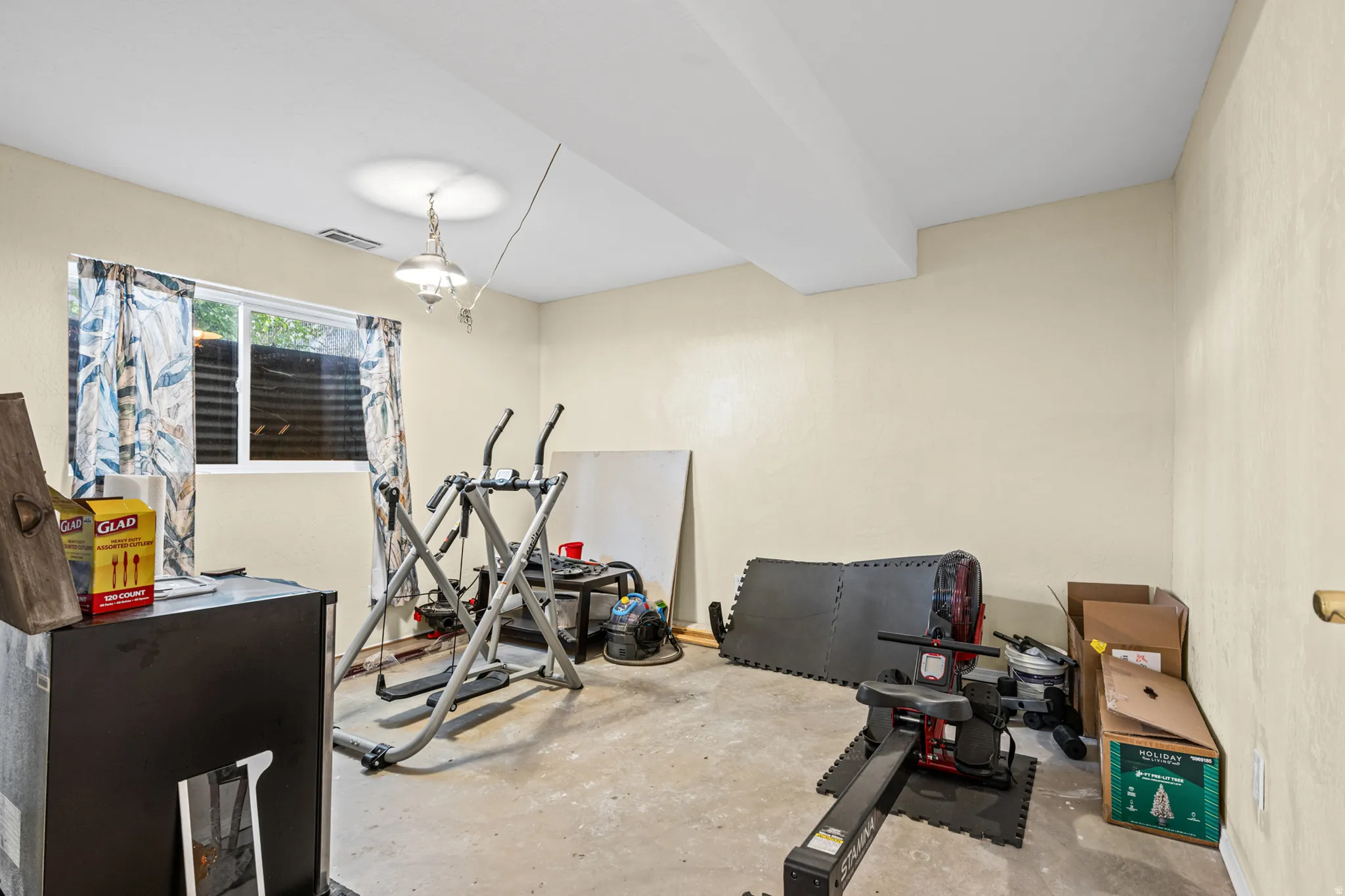 Versatile interior space featuring light-colored walls and a concrete floor