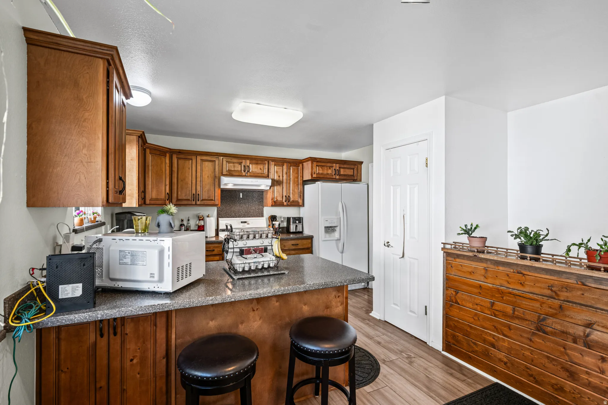 Kitchen featuring wood cabinetry, a breakfast bar with stone-finish countertops, and wood-finish flooring