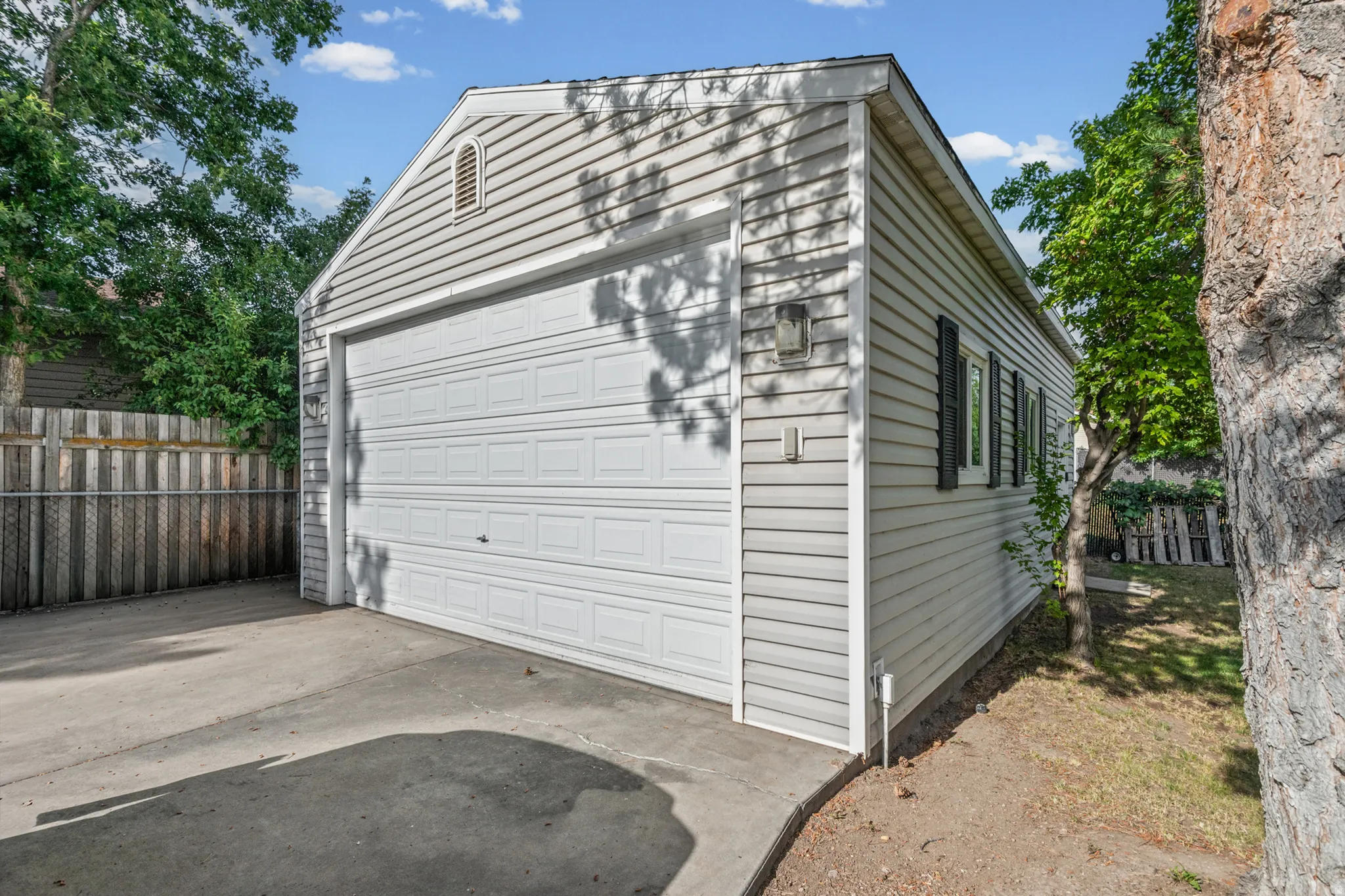 Detached garage featuring horizontal siding, a paneled overhead door, and two windows with dark louvered shutters