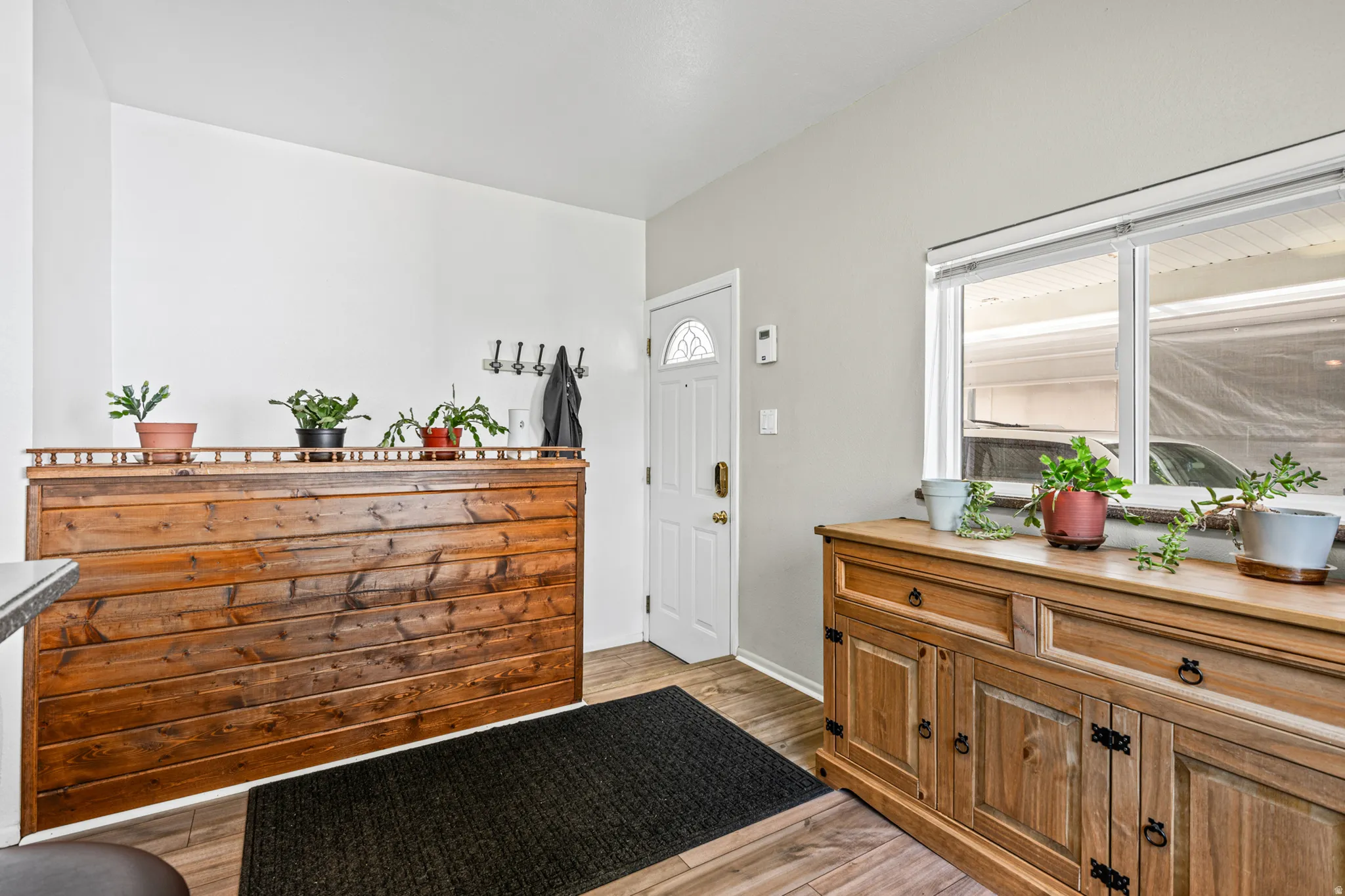 Entryway featuring wood-finish flooring, a white paneled entry door with decorative glass, and a built-in wood divider