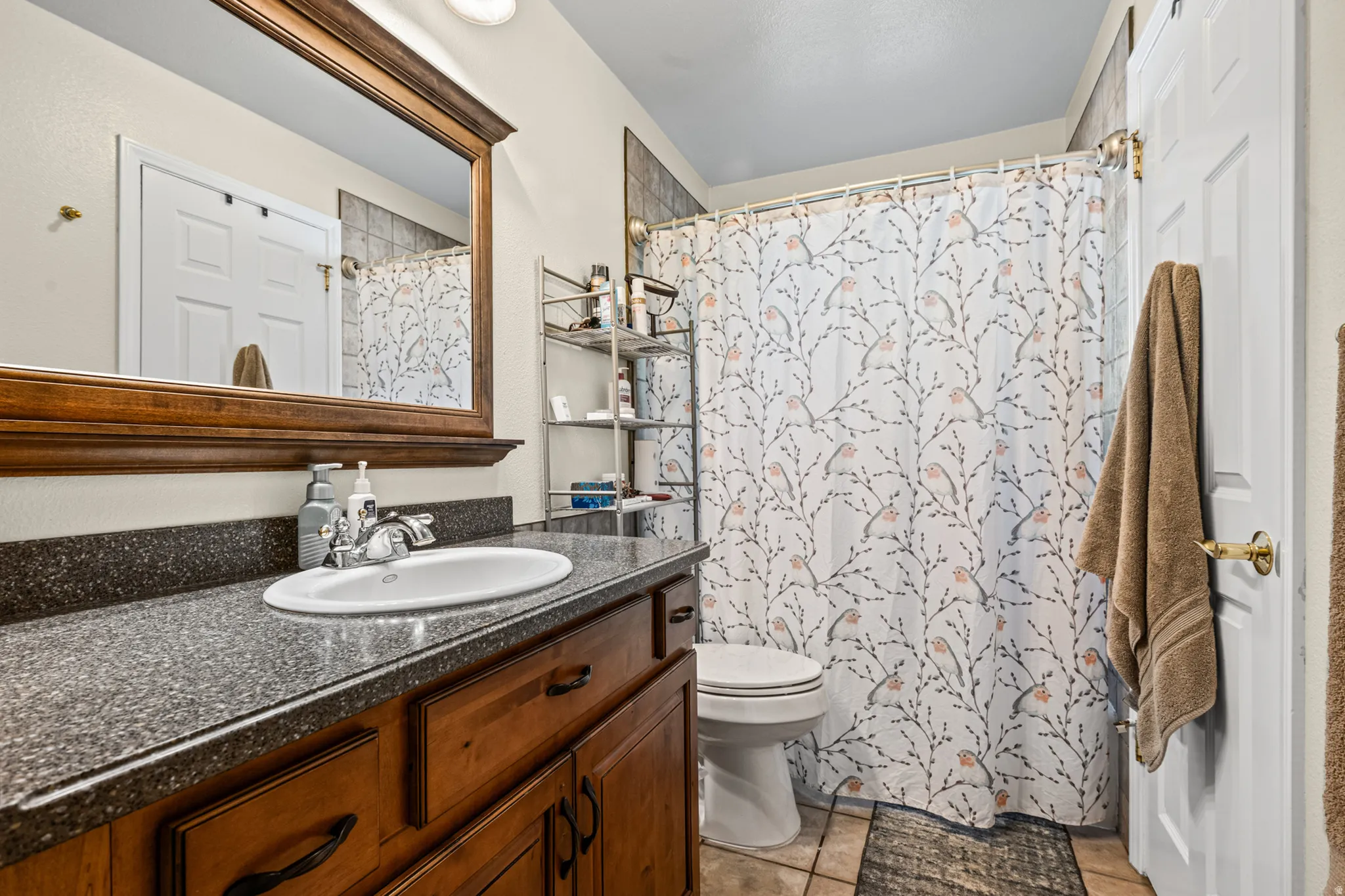 Bathroom featuring a vanity with a dark speckled countertop, an undermount sink, and wood cabinetry
