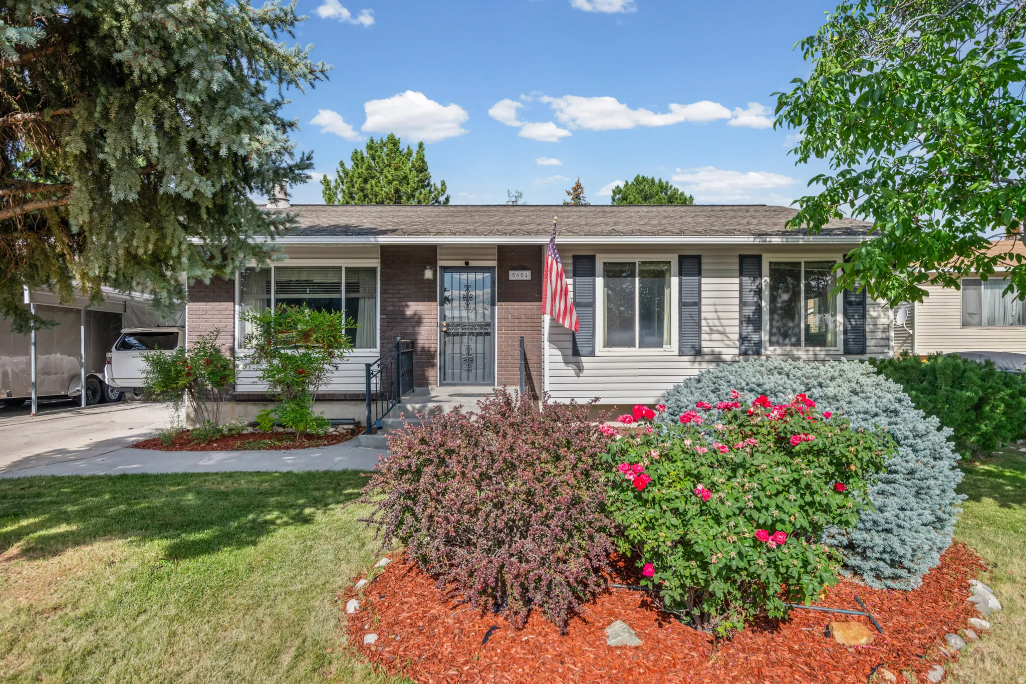 Charming exterior with brick and siding facade, featuring a landscaped front yard with mature plantings and decorative mulch