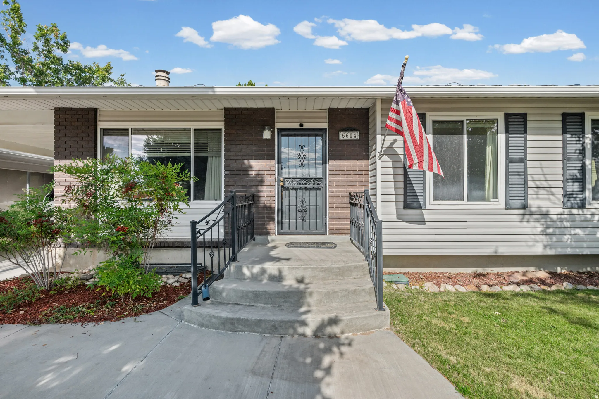 Front exterior featuring light-colored siding, dark brick accents, and a covered entry