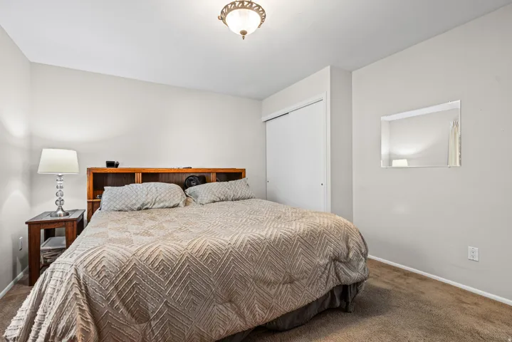 Bedroom featuring light gray wall paint, brown carpeting, and a built-in closet with sliding doors
