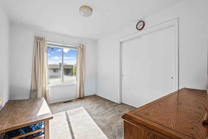Carpeted interior space featuring a large window with drapes, a flush mount ceiling light, and a white sliding closet door