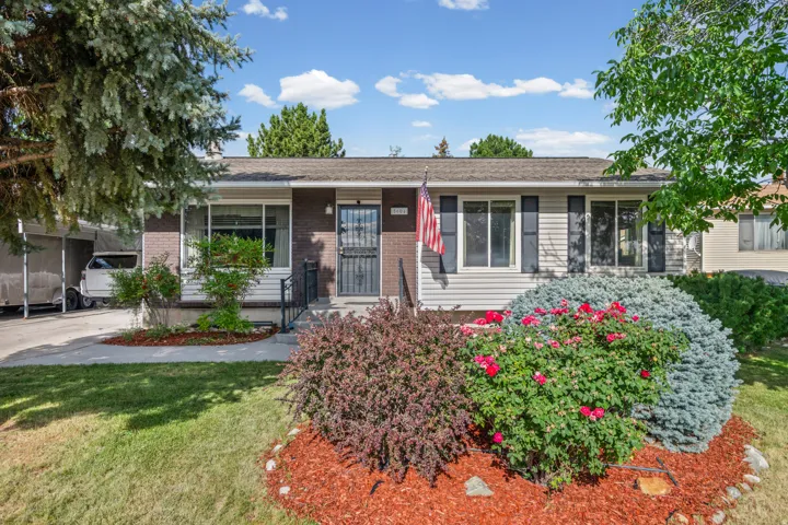 Charming exterior with brick and siding facade, featuring a landscaped front yard with mature plantings and decorative mulch
