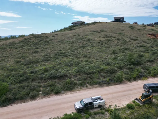 Expansive hillside lot featuring natural shrubbery and a dirt road frontage