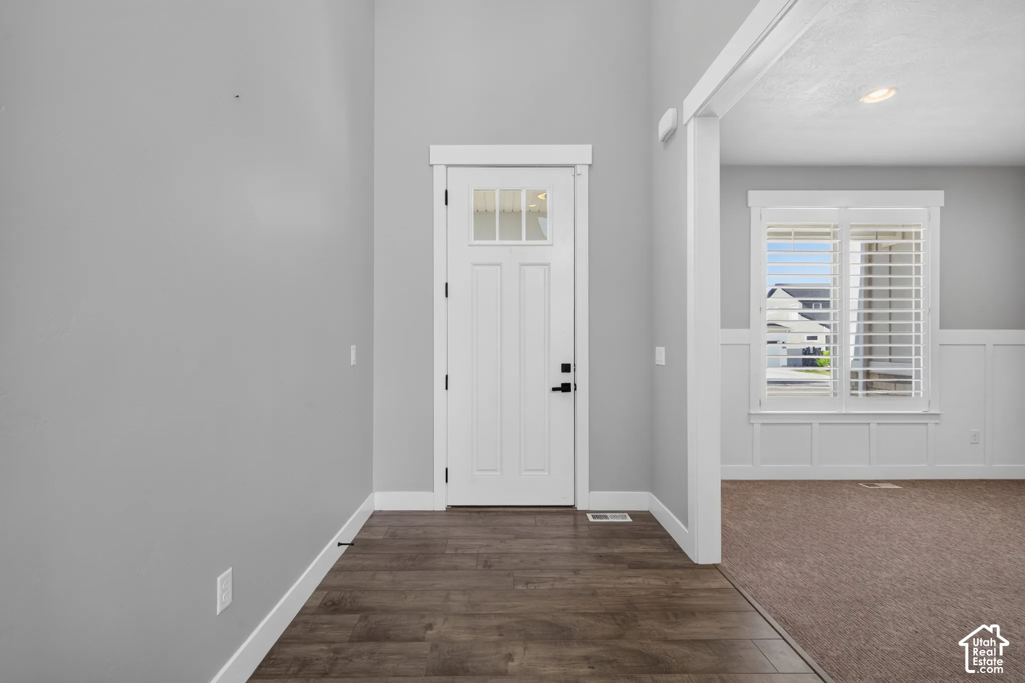 Entryway featuring wood-finish flooring, a paneled door with glass inserts, and a transom window