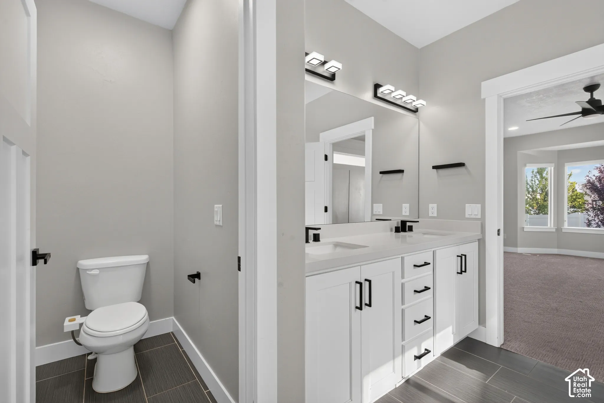 Dual vanity with white cabinetry and integrated sinks, matte black fixtures, and a large mirror with contemporary lighting