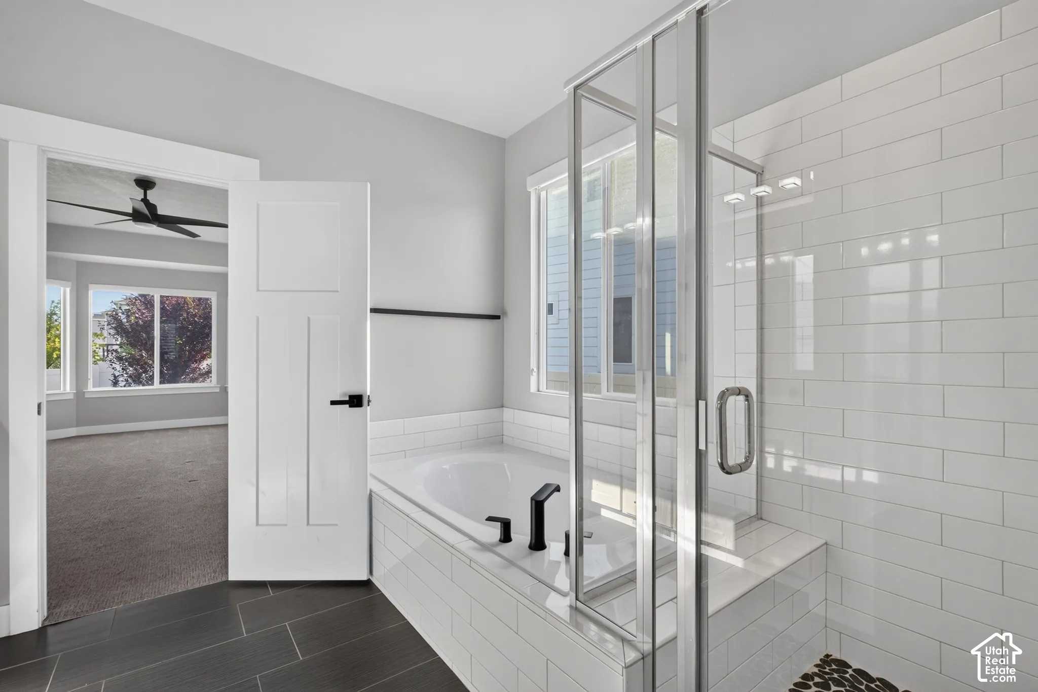 Contemporary bathroom featuring a built-in tub with matte black fixtures, a separate glass-enclosed shower with subway tile walls, and dark rectangular floor tiles
