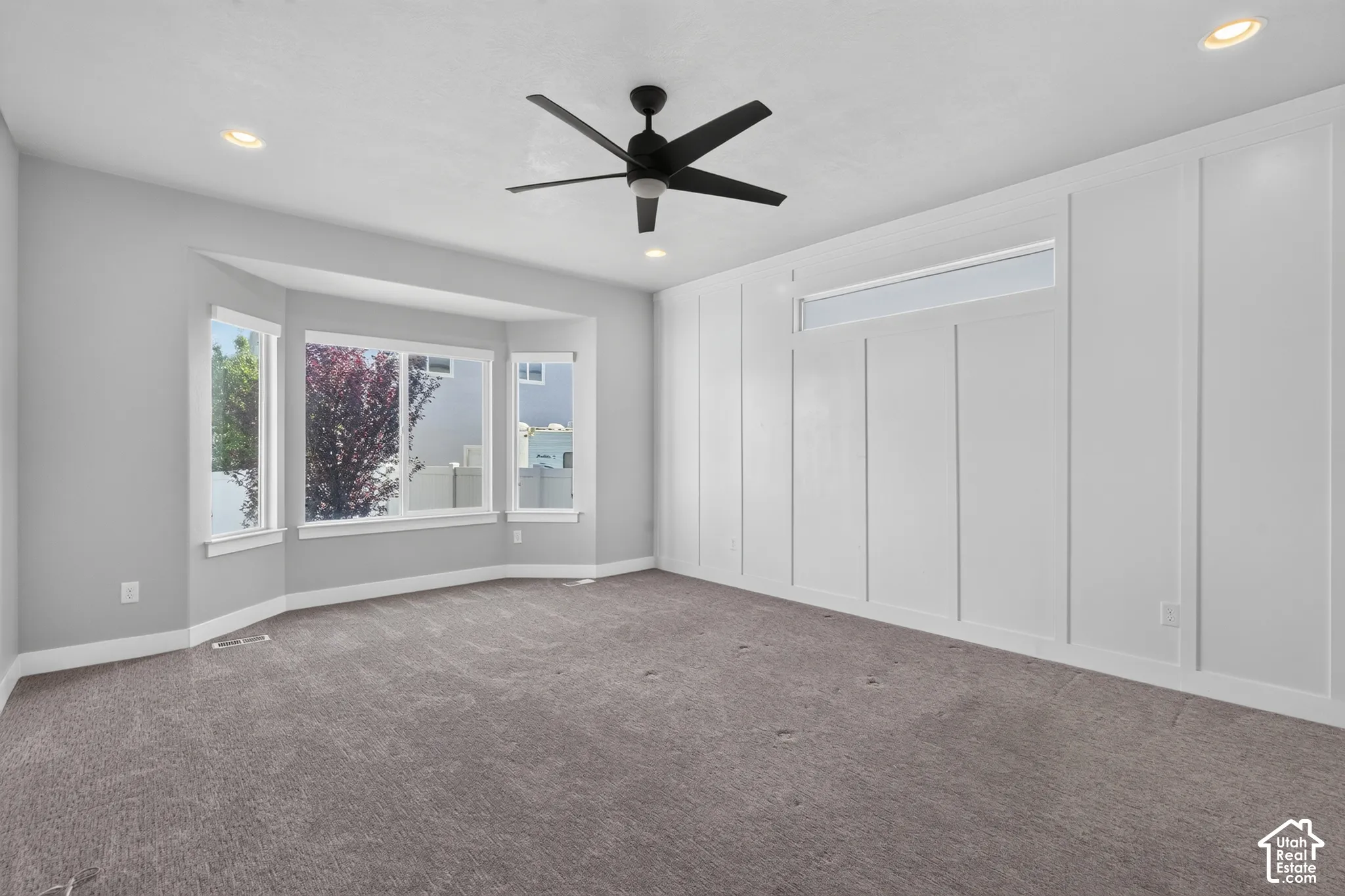 Spacious room featuring gray carpeting and a prominent bay window