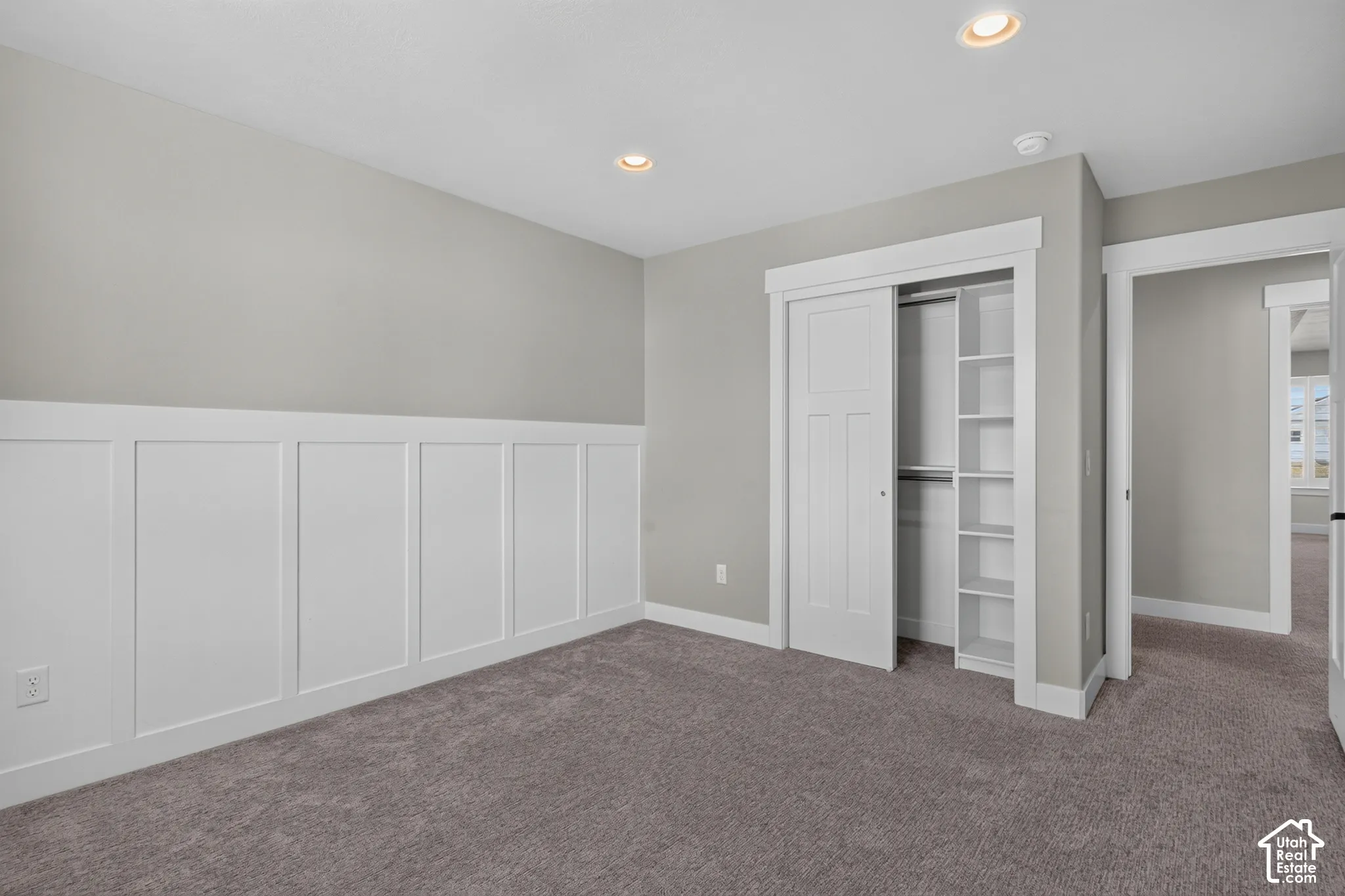 Carpeted room featuring wainscoting, recessed lighting, and a closet with bifold doors and built-in shelving