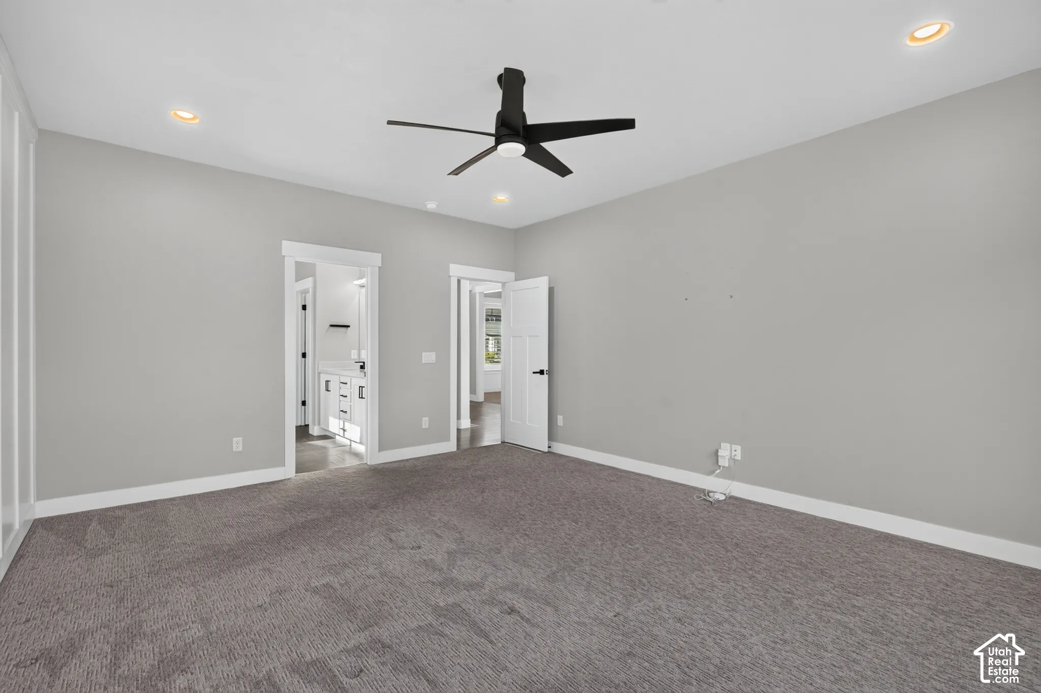 Spacious carpeted room featuring a ceiling fan, recessed lighting, and white trim molding