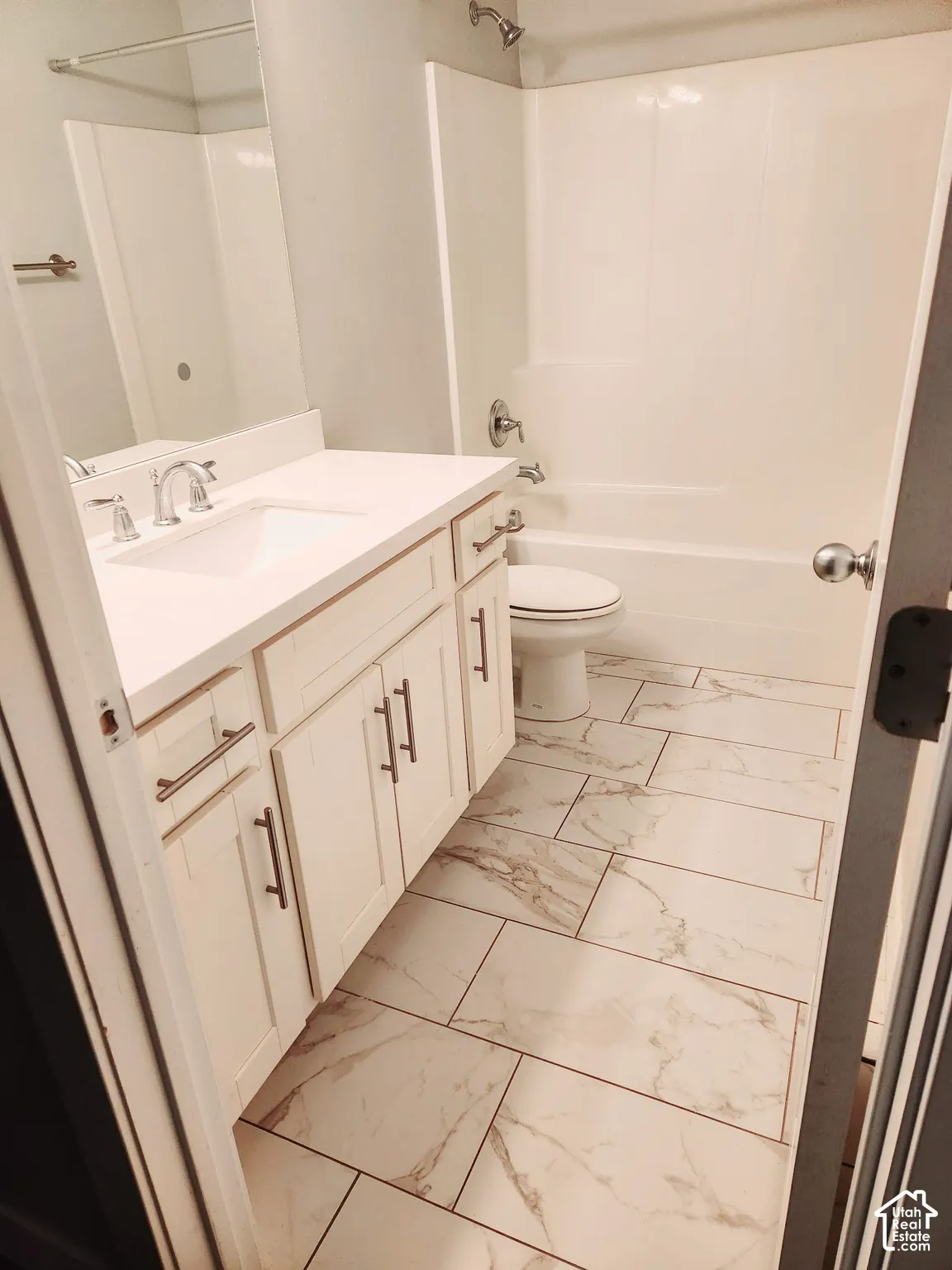 Bathroom featuring a white vanity with an integrated sink, brushed nickel faucet, and under-sink cabinetry with modern hardware