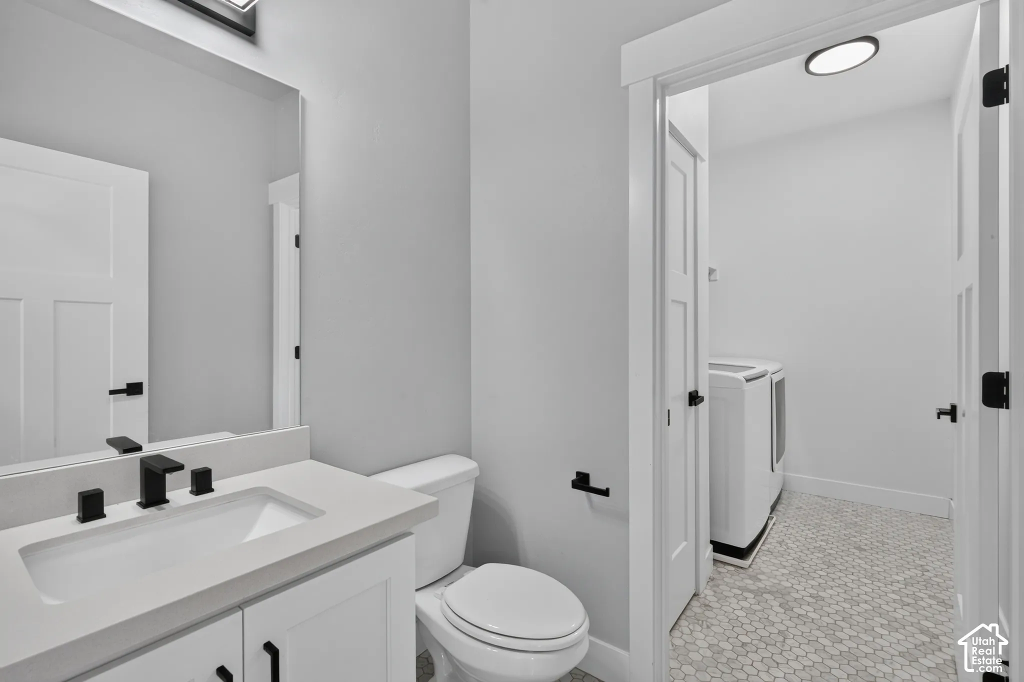 Bathroom vanity featuring a rectangular integrated sink, light-toned countertop, and matte black faucet
